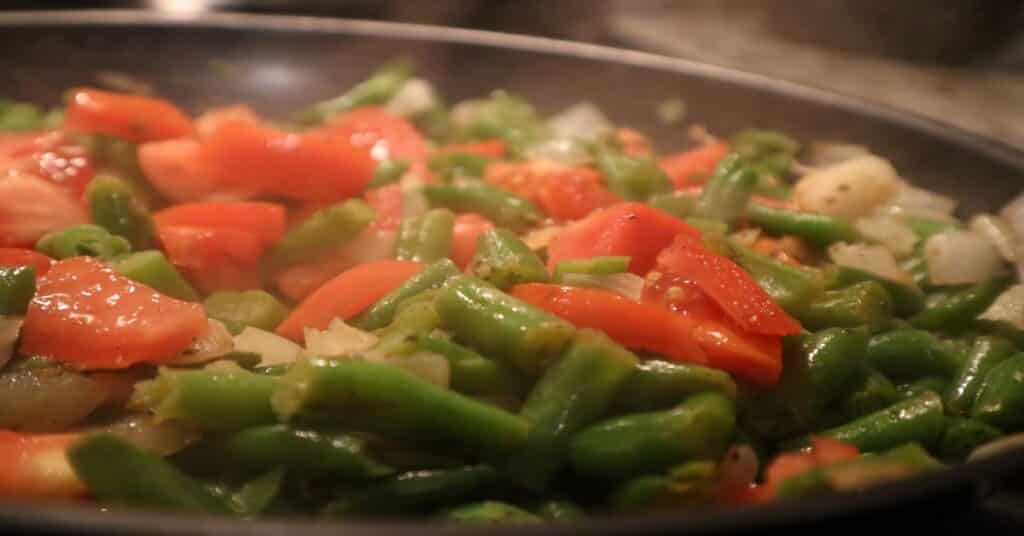 Sautee green beans with onions, garlic, and tomatoes