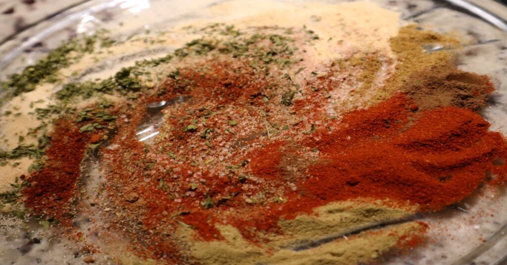 dry Indian spices and herbs in a swirling circle on a clear glass plate