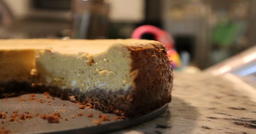 Easy Sugar-free Keto Low Carb Pumpkin Cheesecake on kitchen counter with a slice cut out of it