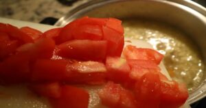 Adding tomato to pot during cooking process of lentil recipe or lentil soup recioe