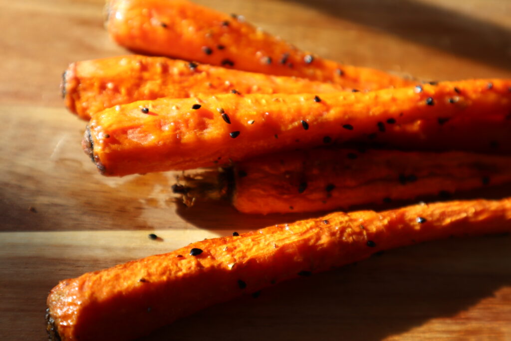 Roasted Carrots with nigella seeds after roasting on a light wood colored cutting board