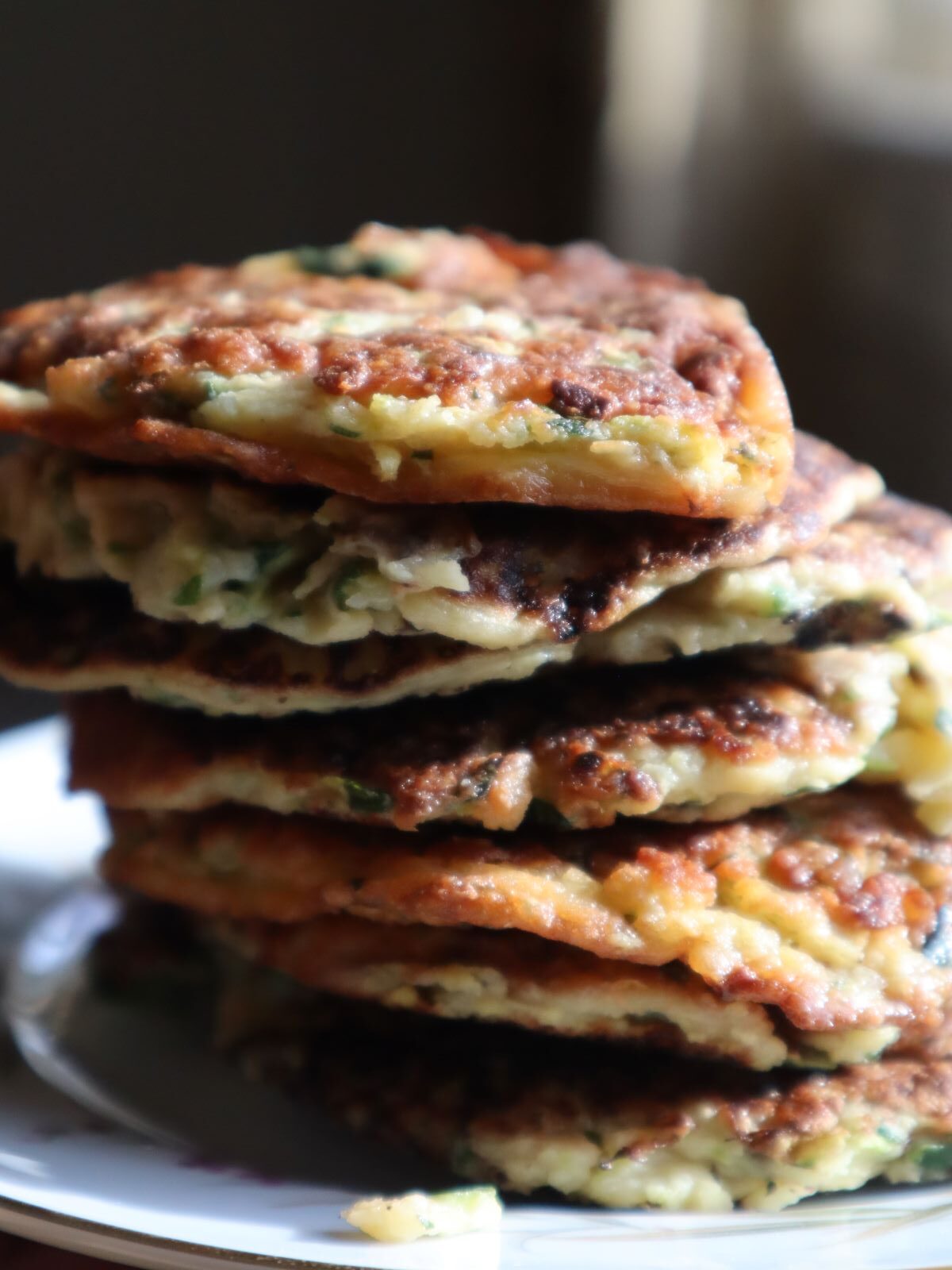 Savory Zucchini fritters/pancakes stacked on a white plate