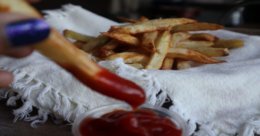 Crispy Homemade Air Fryer French Fries with one dipped in ketchup