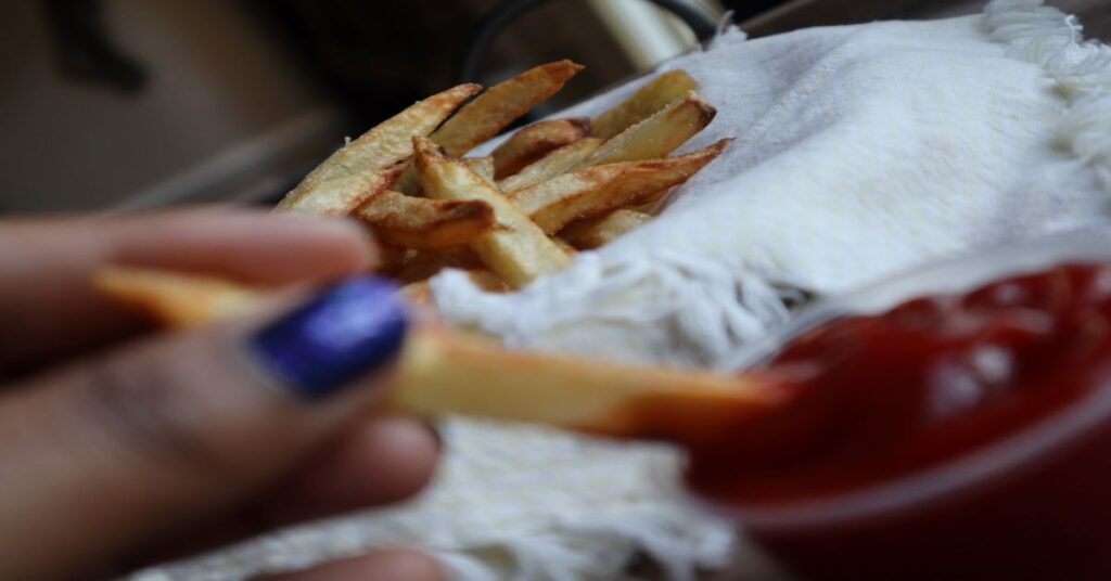 Crispy Homemade Air Fryer French Fries in a basket with ketchup and fry dipped in ketchup visible