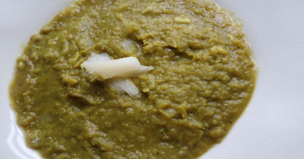 Green Split Pea Soup in a white bowl decorated with slivers of cassava on top the soup