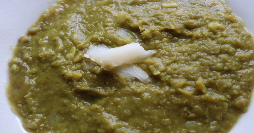 Green Split Pea Soup in a white bowl decorated with slivers of cassava on top the soup