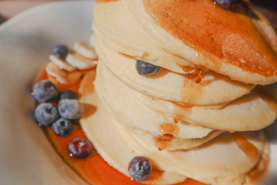 Stack of pancakes with maple syrup. Topped with fresh blueberries