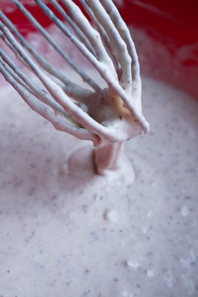 Pancake batter with whisk shown with batter dripping