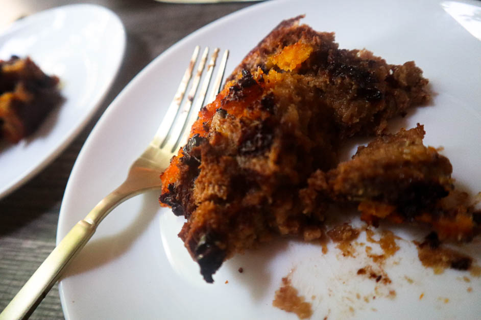Chocolate orange bread pudding in two separate white plates with a spoon of orange marmalade between them