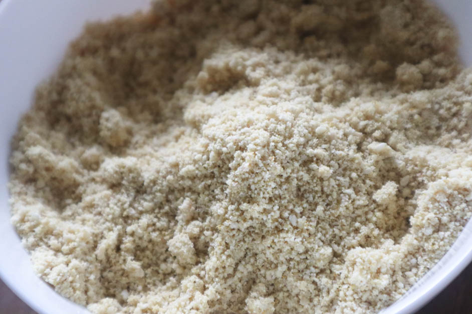 Close up of vegan parmesan cheese crumbles in a large white bowl.